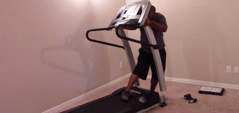 A person disassembling a treadmill
