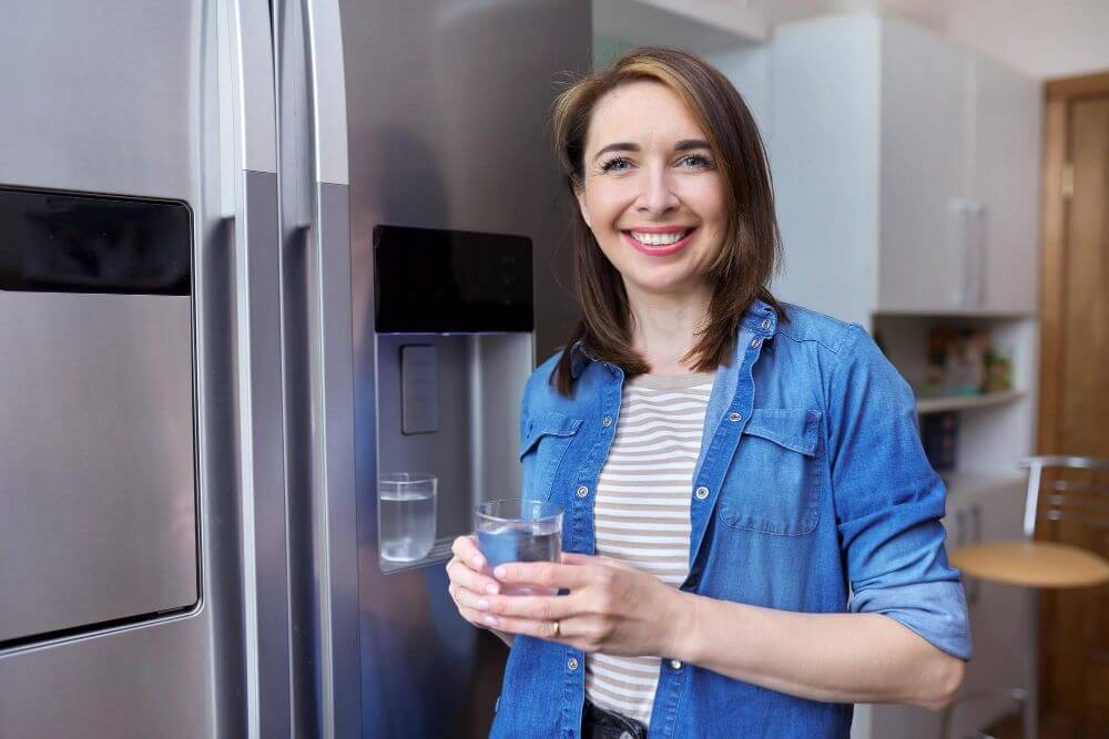 Pretty lady pouring water from fridge