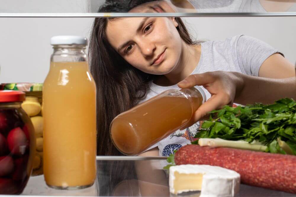 A woman taking out a bottle of onion juice from the refrigerator